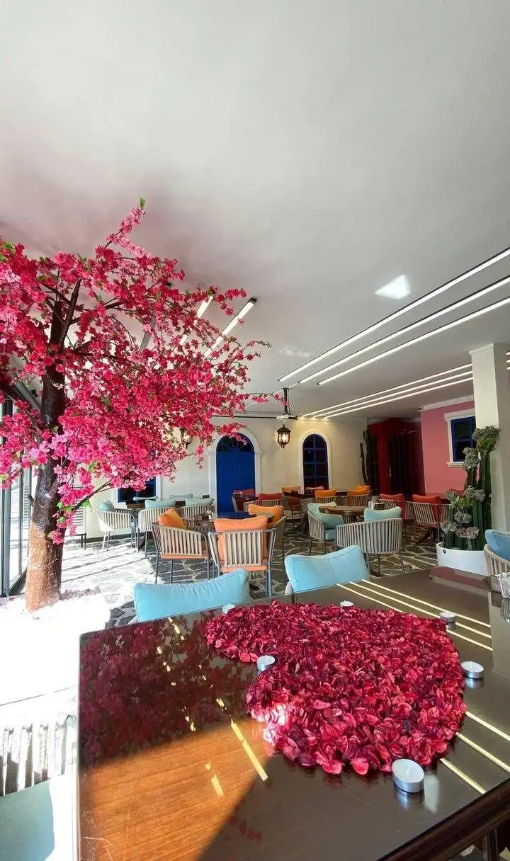 فضای داخلی کافه رستوران بلوکازا با درخت شکوفه گیلاس صورتی، دکوراسیون مدرن و رمانتیک برای تجربه غذایی دلنشین.