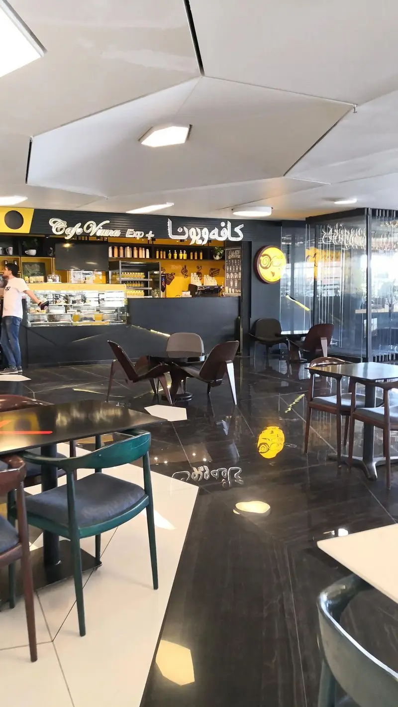 محیط دلباز و طراحی داخلی نوین کافه ویونا، فودکورت رویال، با تاکید بر جزئیات زیبای دکوراسیون، چیدمان میز و صندلی‌ها و نورپردازی دلنشین.