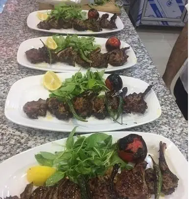 چندین بشقاب شیشلیک لذیذ و کباب دنده گریل شده اعلا به همراه گوجه، فلفل کبابی، سبزیجات تازه و لیمو در کباب مجلل ساوالان.