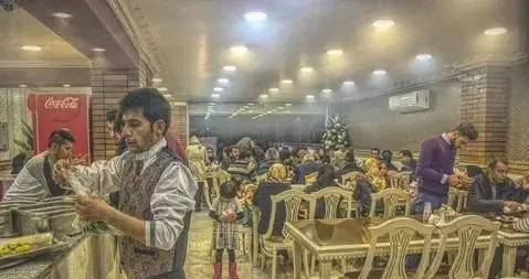 رستوران کباب مجلل ساوالان: نمایی از سالن غذاخوری با مشتریان در حال لذت بردن از غذا و کارکنان در حال ارائه خدمات عالی. فضایی دلپذیر برای تجربه طعم لذیذ کباب.