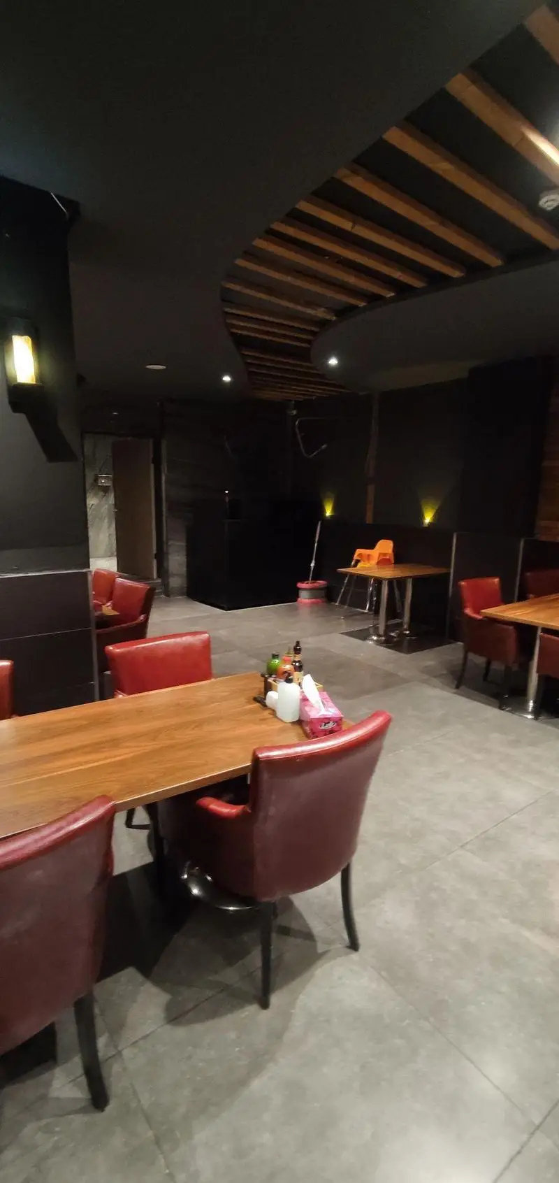 فضای داخلی لوکس رستوران ایتالیایی مریخ با میزهای چوبی، صندلی‌های قرمز چرمی و سقف دکوراتیو. محیطی مدرن برای تجربه غذای ایتالیایی.