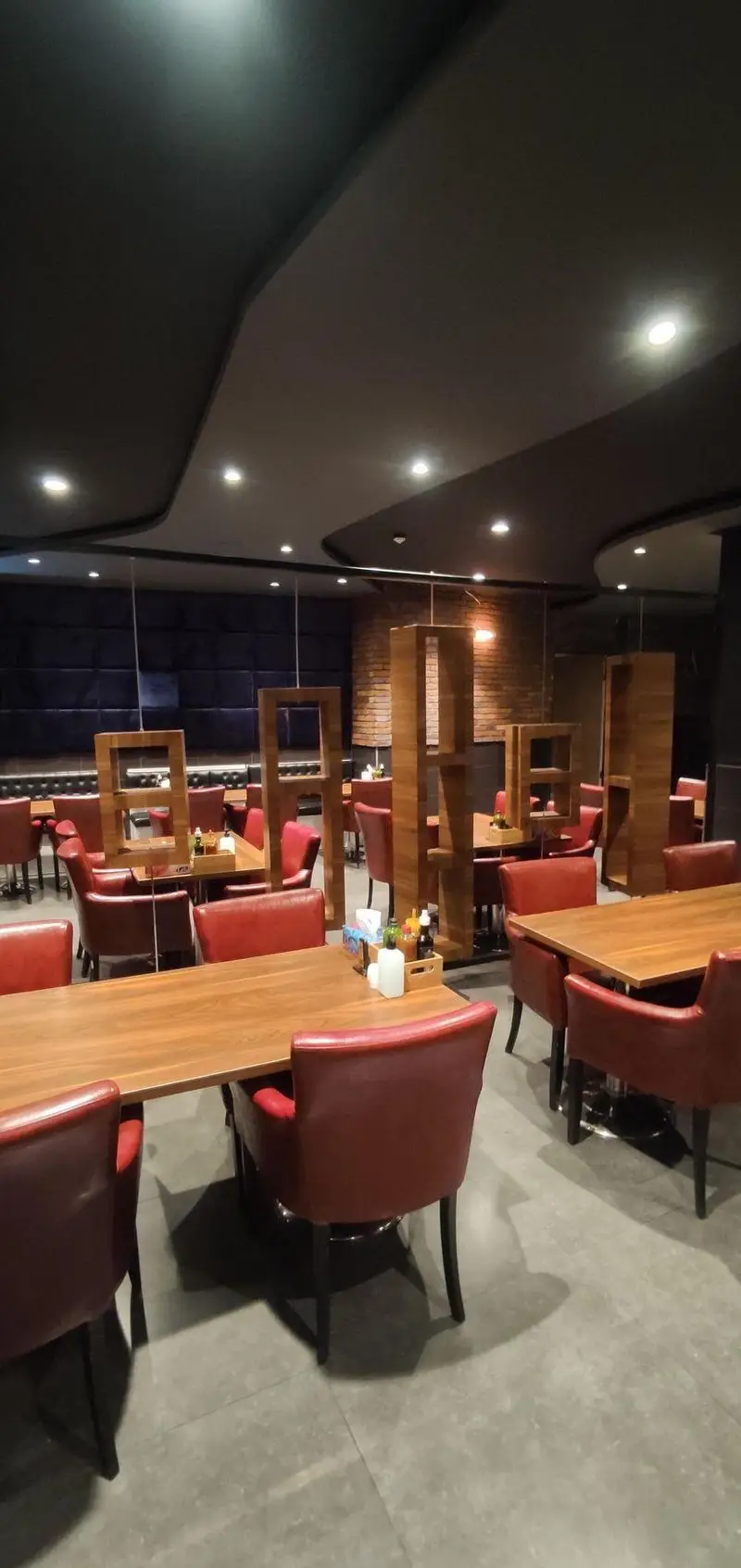 فضای داخلی مدرن و شیک رستوران ایتالیایی مریخ با میزهای چوبی، صندلی‌های چرمی قرمز و سقف دکوراتیو برای تجربه‌ای دلنشین.