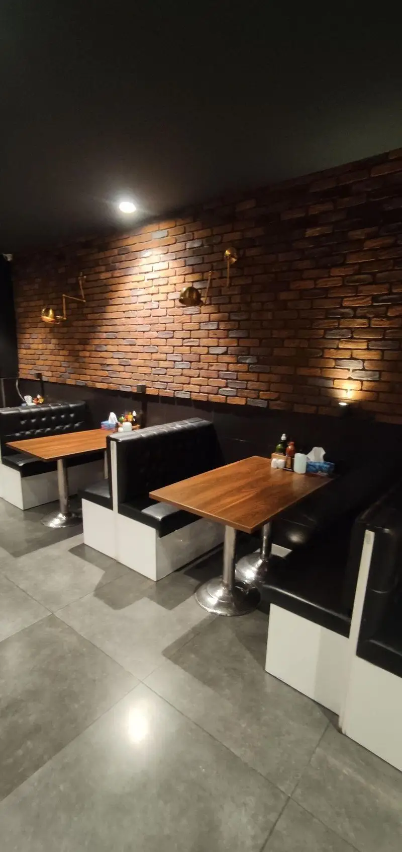 نمایی داخلی از رستوران ایتالیایی مریخ با دیوارهای آجری، سقف مشکی، میزهای چوبی و مبلمان شیک، فضایی دلنشین و مدرن