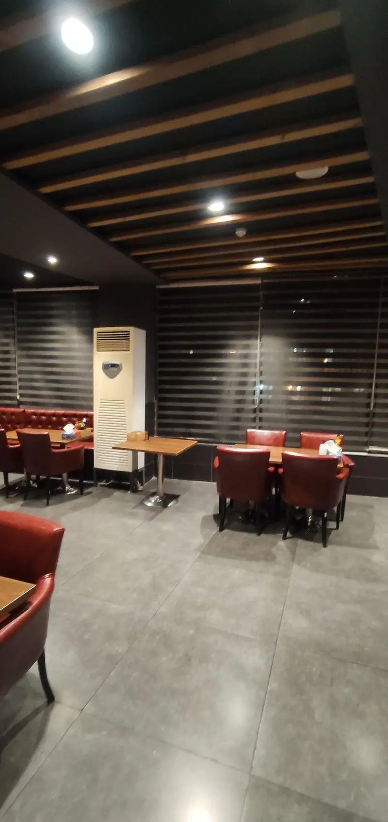 رستوران ایتالیایی مریخ: فضای داخلی مدرن با سقف چوبی، مبلمان چرمی قرمز، میزهای چوبی و کفپوش سنگی براق. محیطی دنج و شیک برای تجربه غذایی دلنشین.