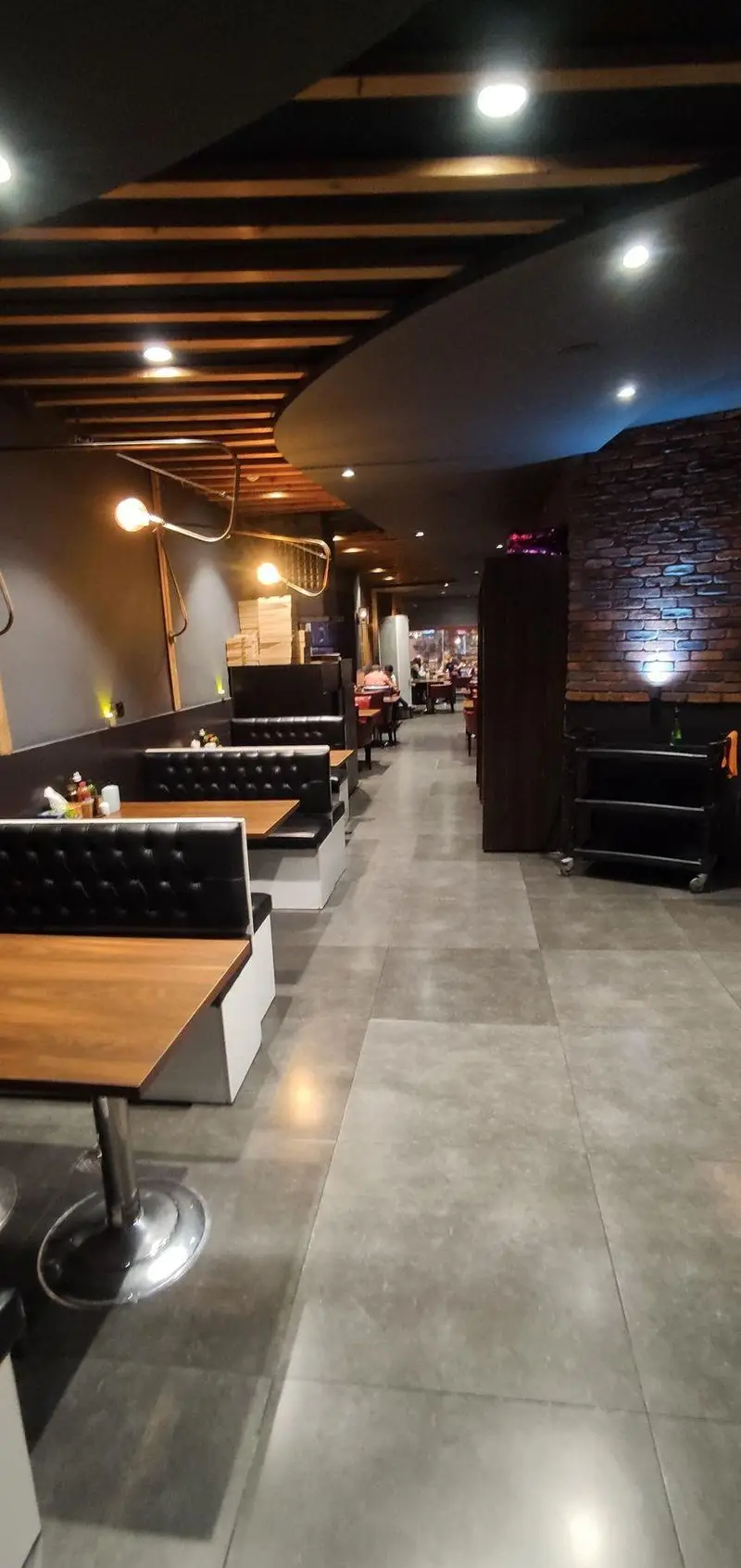 فضای داخلی مدرن و شیک رستوران ایتالیایی مریخ با میز و صندلی‌های راحت، سقف چوبی و آجری، محیطی دلنشین و دنج برای تجربه غذاخوری.