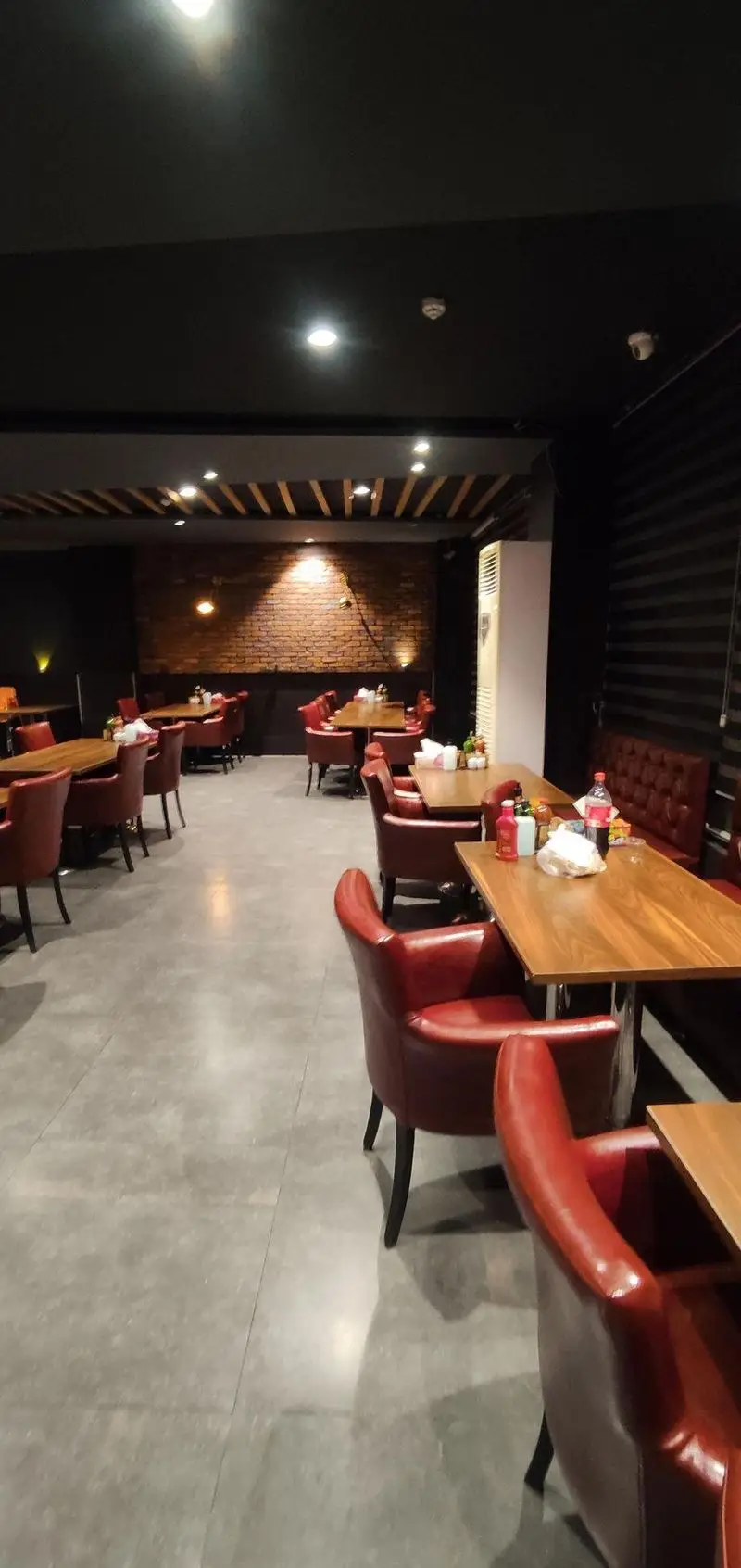 فضای داخلی لوکس رستوران ایتالیایی مریخ: میز و صندلی‌های چوبی و چرم قرمز، دیوار آجری و نورپردازی گرم، محیطی شیک و دلنشین.