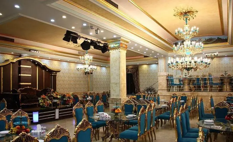 دکوراسیون داخلی مجلل رستوران شفیعی برای برگزاری مراسم با میز و صندلی‌های طلایی و آبی، لوسترهای زیبا و نورپردازی حرفه‌ای.