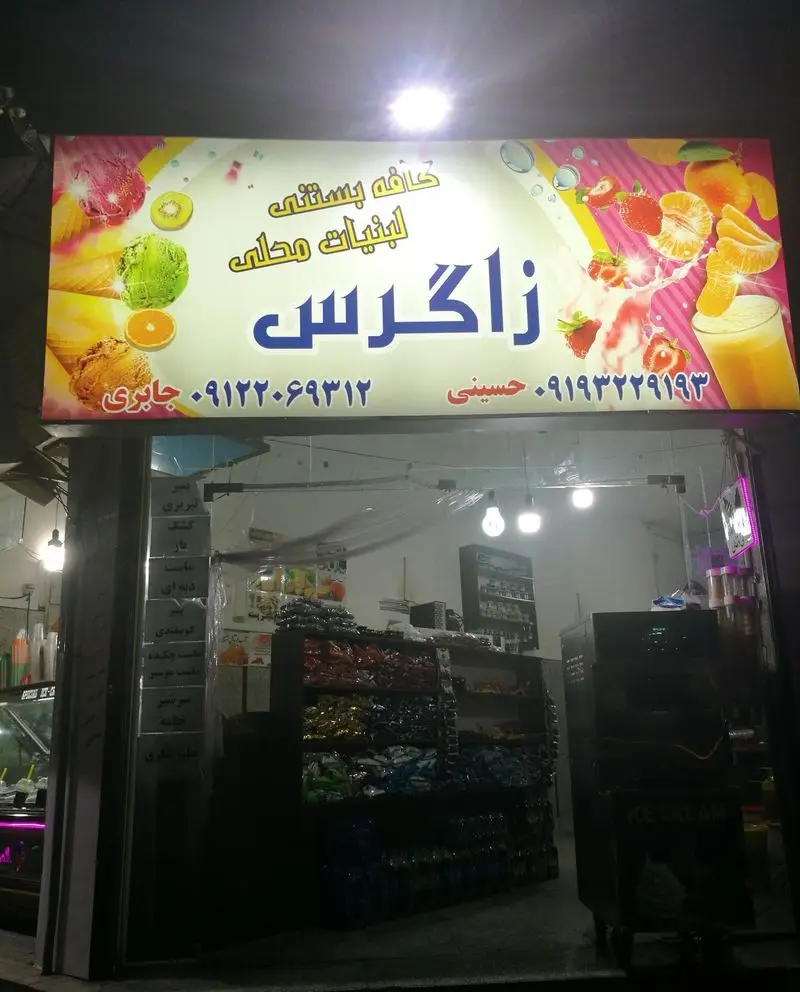 تابلوی پرنور و ورودی کافه بستنی و لبنیات محلی زاگرس، نمایش بستنی، میوه‌های تازه، آبمیوه، و محصولات لبنی و شیرینی.