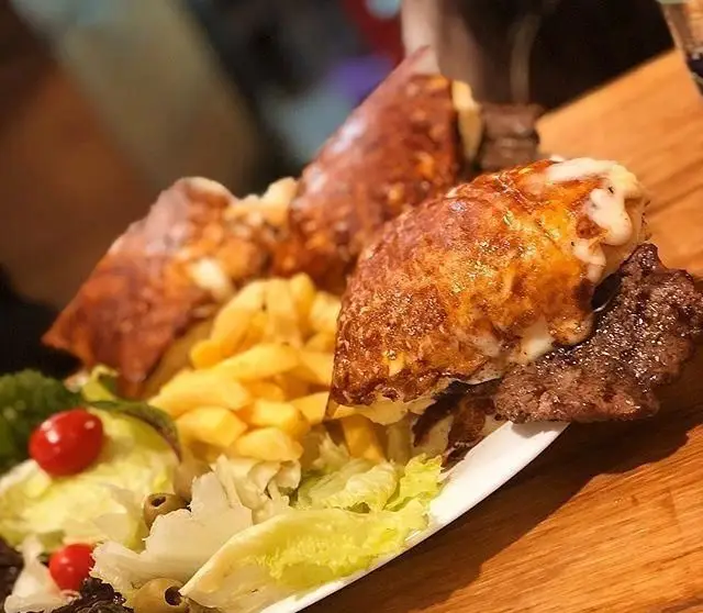 بشقاب غذای فست فود مازی فود شامل رول های گوشت و پنیر گریل شده طلایی، سیب زمینی سرخ کرده و سالاد تازه با گوجه گیلاسی و زیتون. یک وعده کامل و خوشمزه.