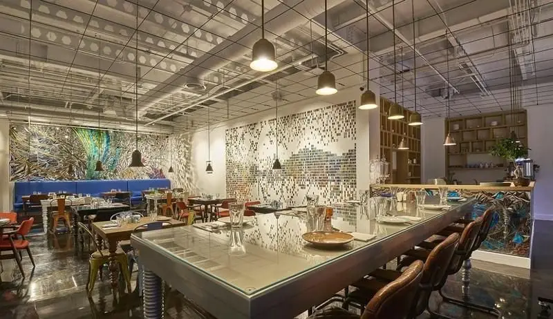 نمای داخلی شیک رستوران ماهی سفید با دکوراسیون مدرن، میزهای چوبی، دیوارنگاری هنری و نورپردازی جذاب برای تجربه غذاخوری دلپذیر.