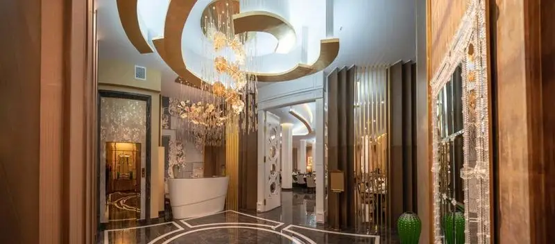ورودی مجلل رستوران ماهان شاندیز شریعتی با دکوراسیون داخلی لوکس، سقف کناف، لوستر طلایی بزرگ و کفپوش مرمر شیک.
