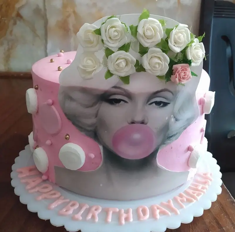 کیک تولد صورتی شیک با طرح مرلین مونرو در حال باد کردن آدامس و تاج گل رز، مناسب جشن مهسا از شیرینی فروشی توحیدی.