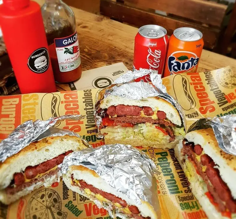 ساندویچ‌های خوشمزه و پرطرفدار فست فود برگریچ شامل هات داگ و برگر، با سس کچاپ برگریچ و نوشابه‌های خنک کوکاکولا و فانتا.