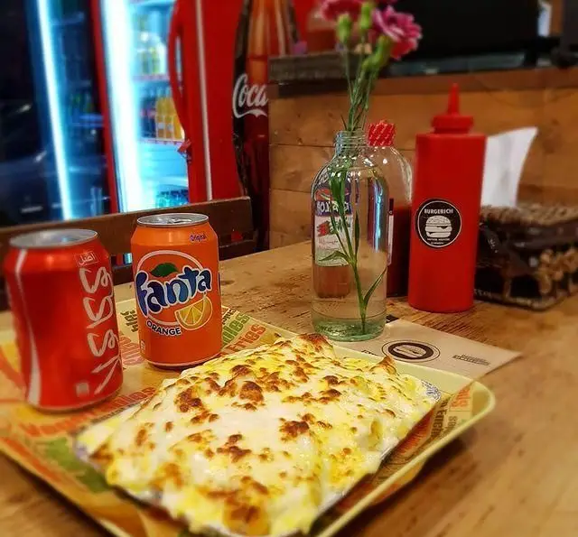 سفارش غذای پنیری داغ و لذیذ در فست فود برگریچ، با نوشابه‌های خنک کوکاکولا و فانتا، آماده سرو در محیطی دلنشین و شاداب.