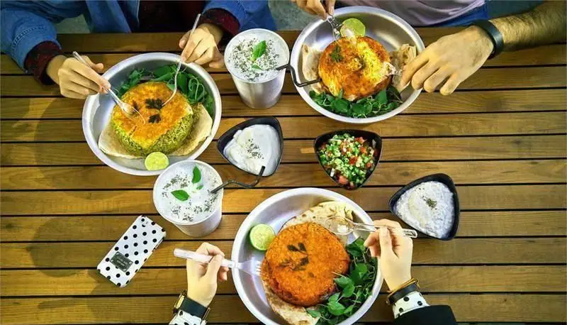 افرادی در حال صرف غذای خوشمزه و سالم در پلاتین فود گاردن، تجربه‌ای دلپذیر از محیط رستوران با غذاهای متنوع.