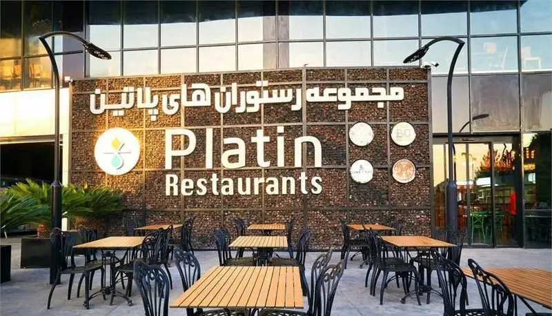 تصویری از فضای باز مجموعه رستوران های پلاتین با میزهای چوبی شیک و صندلی‌های فرفورژه، محیطی دلنشین و مدرن برای مشتریان.