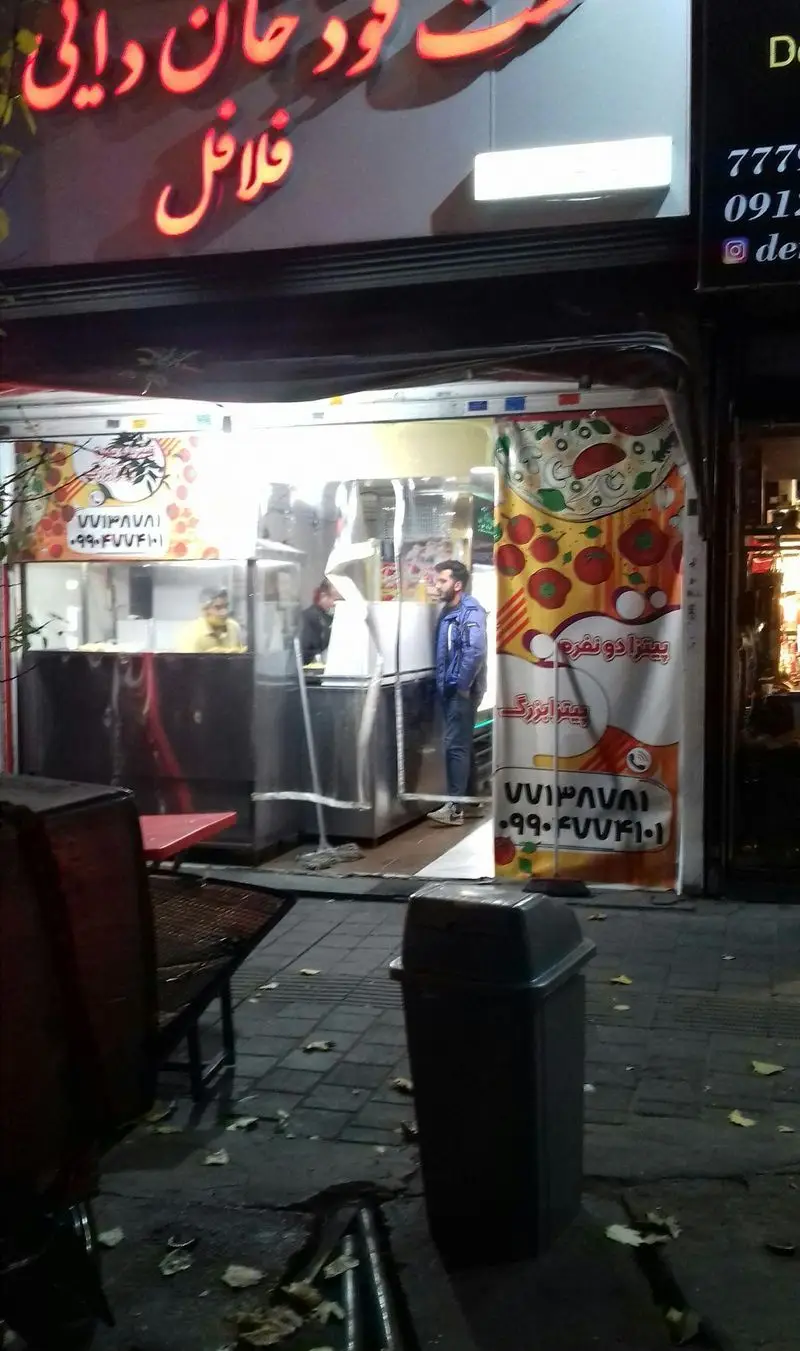 نمای شبانه فست فود پیتزا خان دایی، تابلوی نئون پیتزا خان دایی و فلافل، بنرهای پیتزا و شماره تماس برای سفارش