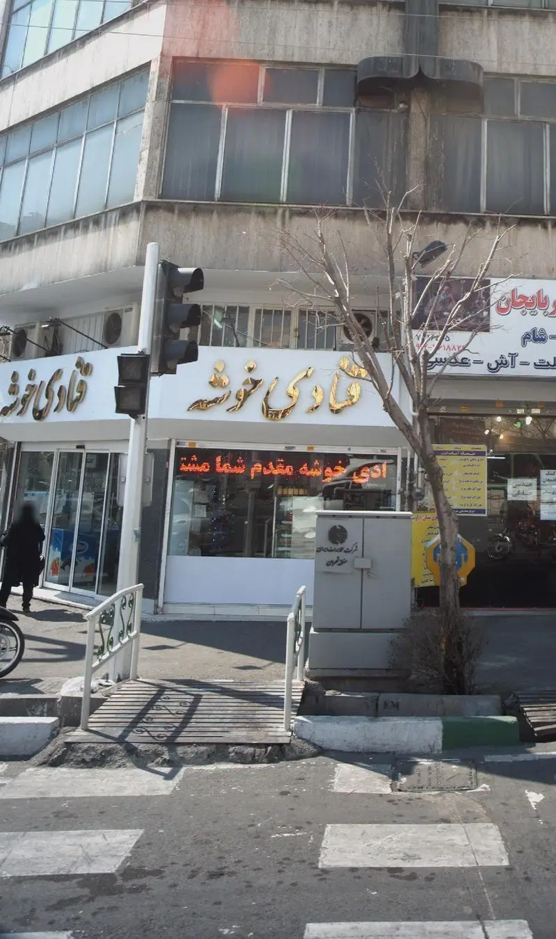 نمای بیرونی قنادی خوشه، فروشگاه شیرینی و کیک تازه، با تابلوی طلایی درخشان و درب ورودی شیشه‌ای در خیابان.