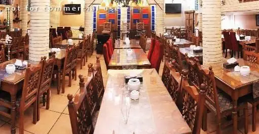 سفره خانه سنتی سماع، نمایی از فضای داخلی با معماری سنتی و دکوراسیون چشم‌نواز، میزهای چوبی زیبا و صندلی‌های طرح‌دار برای تجربه غذای اصیل.