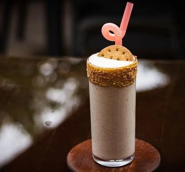 میلک شیک خاص و خوشمزه کافه رستوران کاسا دل شف با لبه بیسکویتی، کوکی رویی و نی صورتی، تجربه نوشیدنی دلپذیر.