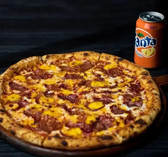 پیتزا ایتالیایی گوشت و پنیر از منو کافه رستوران کاسا دل شف، با نان برشته و تکه‌های لذیذ گوشت. همراه با نوشابه پرتقالی فانتزی خنک.