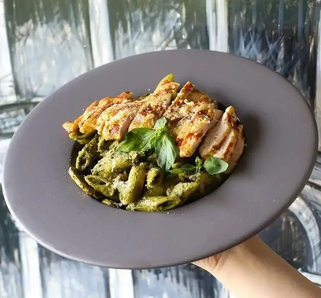 پاستا پنه با سس پستو سبز و مرغ گریل شده برش خورده در کافه رستوران کاسا دل شف. یک غذای ایتالیایی خوشمزه برای ناهار یا شام.