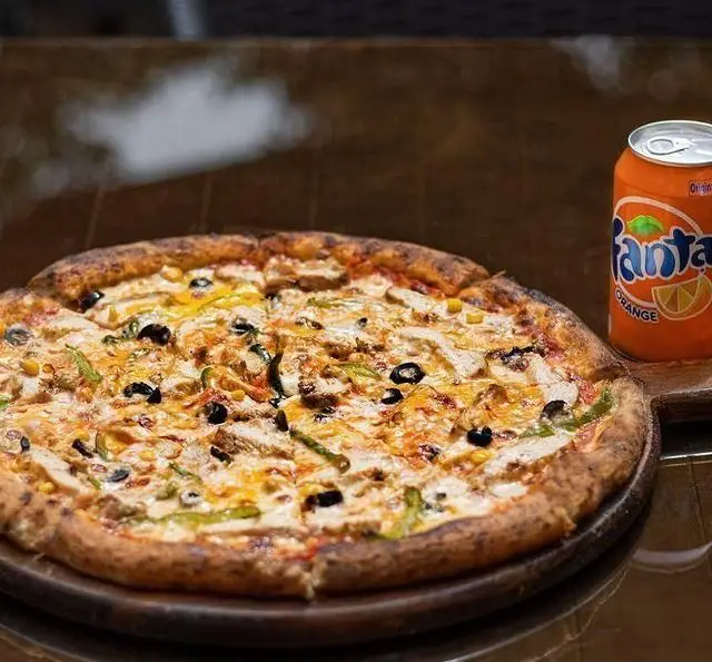 پیتزای داغ و تازه مرغ، زیتون، فلفل دلمه‌ای و ذرت همراه با نوشابه فانتا در کافه رستوران کاسا دل شف