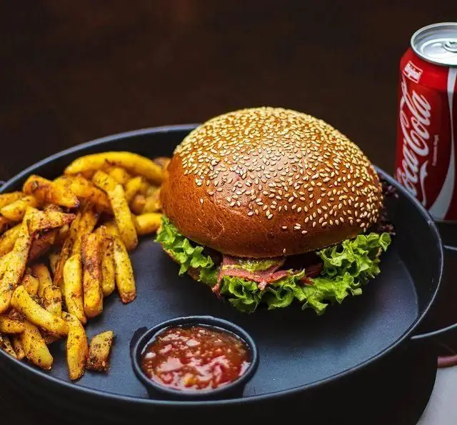 وعده غذایی لذیذ کافه رستوران کاسا دل شف: برگر با نان کنجدی، سیب زمینی سرخ کرده، سس و نوشابه کوکاکولا.