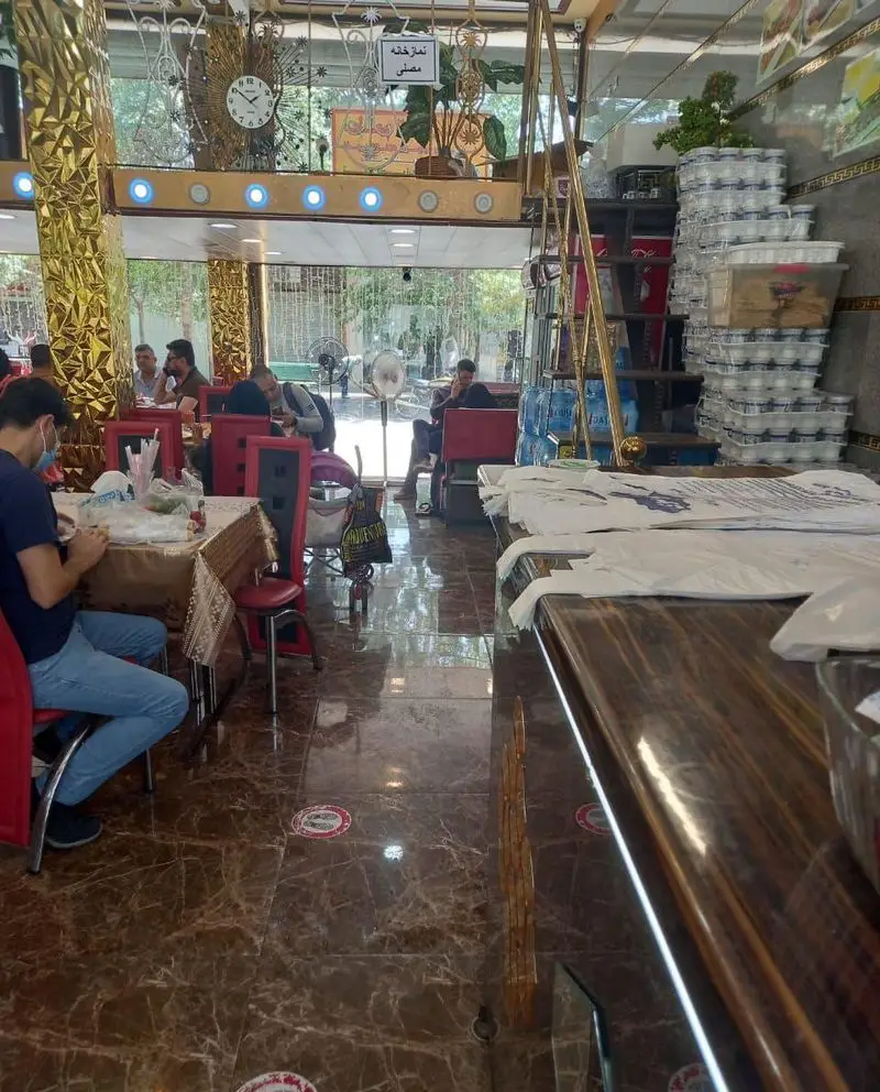 نمای داخلی رستوران موسوی با مشتریانی مشغول غذا خوردن، دکوراسیون شیک طلایی و کفپوش سنگی براق. محیطی دلنشین برای صرف وعده غذایی.