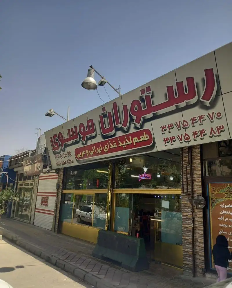 تصویر نمای بیرونی رستوران موسوی، با تابلوی روشن که ارائه دهنده طعم لذیذ غذای ایرانی و عربی است.
