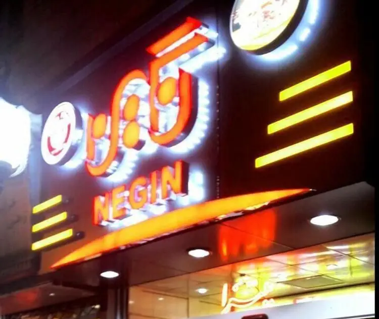 تابلوی نئون درخشان پیتزا نگین (Negin Pizza) به زبان فارسی و انگلیسی در شب، نمای ورودی یک رستوران فست فود مدرن و جذاب با نورپردازی خاص.