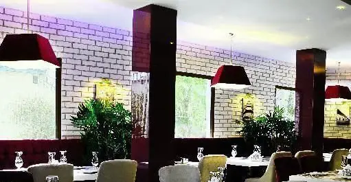 فضای داخلی دلنشین کافی شاپ تیفانی با دکوراسیون مدرن، دیوارهای آجری سفید، میز و صندلی‌های راحت و نورپردازی گرم برای تجربه‌ای بی‌نظیر.