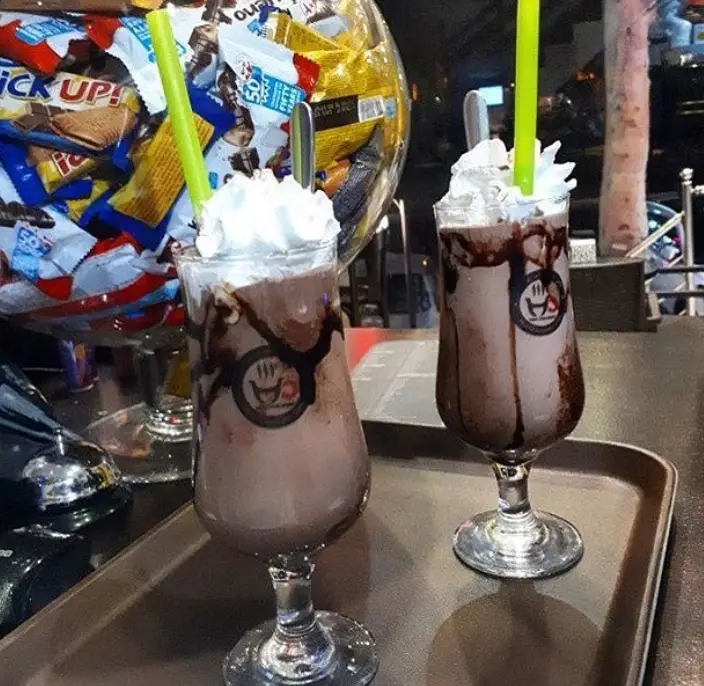 میل شیک شکلاتی یا هات چاکلت با خامه و سس شکلات در منوی کافی شاپ هات چاکلت، تجربه‌ای شیرین و لذت‌بخش.