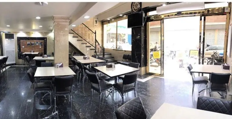 تصویری از فضای داخلی دنج و تمیز رستوران ایرانی برادران حاجی عباسی، با چیدمان میز و صندلی‌های شیک و آماده پذیرایی.