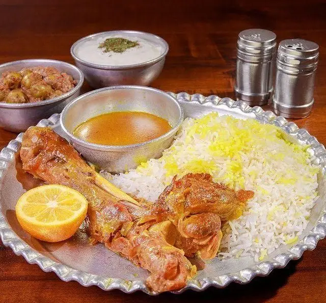 چلو گوشت لذیذ و برنج زعفرانی رستوران ایرانی برادران حاجی عباسی همراه با ماست و خورشت برای تجربه غذای اصیل ایرانی.