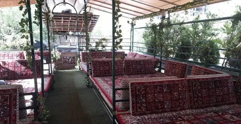 فضای سنتی و دلنشین باغ گیلاس با تخت‌های مفروش و کوسن، مناسب برای استراحت و صرف غذا در دل طبیعت.