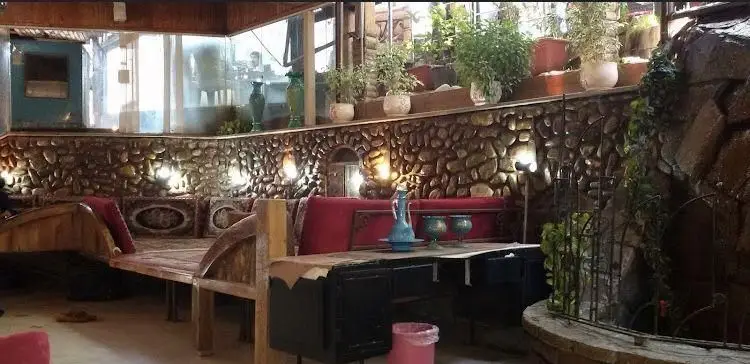 نمای داخلی رستوران سنتی باغ گیلاس با دکوراسیون سنگی، تخت‌های چوبی، فضای سبز و آبنما. محیطی دلنشین و آرامش‌بخش.