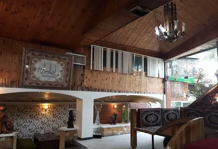 تصویری از فضای داخلی دلنشین و سنتی باغ گیلاس با سقف چوبی، تخت‌های سنتی و تابلوهای نفیس. دکوراسیون خاص و آرامش‌بخش.