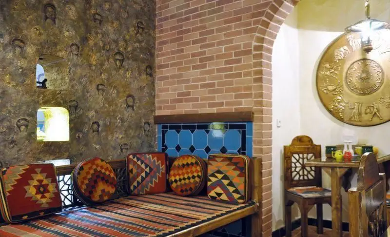 دکوراسیون داخلی سرای سنتی سیمرغ آبی، نمایی از فضای گرم و دلنشین با تخت‌های سنتی، کوسن‌های طرح‌دار و تزئینات اصیل ایرانی.