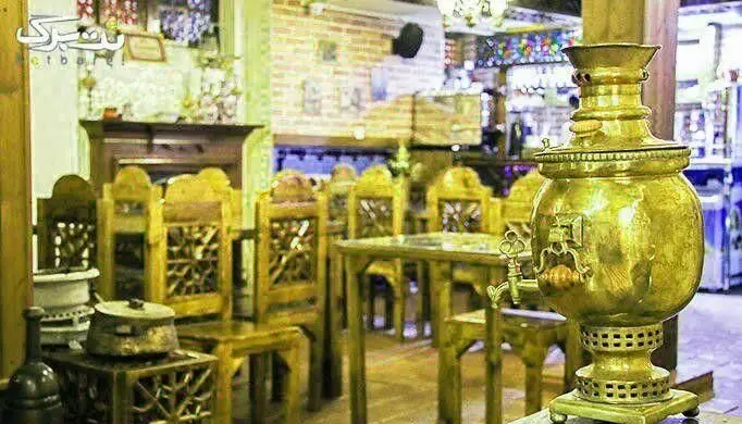 تصویری از داخل سرای سنتی سیمرغ آبی با سماور زیبای برنجی، میز و صندلی‌های چوبی منبت‌کاری شده و فضایی دلنشین.