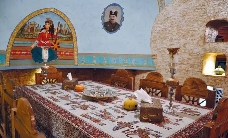 نمایی از فضای داخلی رستوران سنتی سیمرغ آبی با میز ناهارخوری طرح‌دار، نقاشی‌های دیواری و معماری اصیل ایرانی