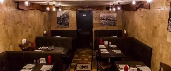 نمای داخلی رستوران ایتالیایی امیرگریل با دکوراسیون سنگی، میز و صندلی‌های راحت و نورپردازی گرم، محیطی دنج برای سرو غذا.