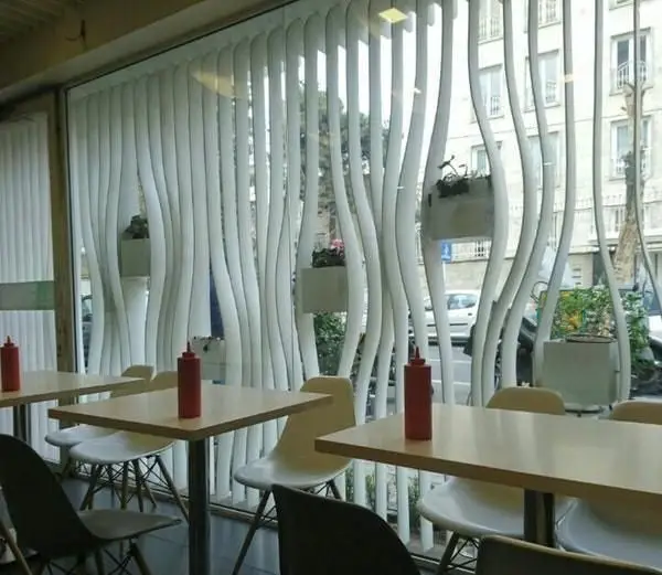 فضای داخلی مدرن و دنج فست فود گیو با طراحی منحصربه‌فرد پنجره و پرده‌های موج‌دار، میز و صندلی‌های شیک و نمایی از شهر.