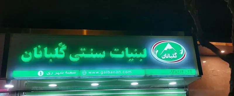 تابلوی نئونی سبز رنگ و روشن فروشگاه لبنیات سنتی گلبانان(هدایتی) در شب، با لوگو کوه و آدرس galbanan.com.