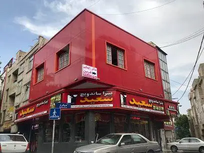 نمای کلی از پیتزا و ساندویچ سعید، یک رستوران فست فود محبوب در ساختمان قرمز رنگ با تابلوی بزرگ و جذاب در خیابان شهر.