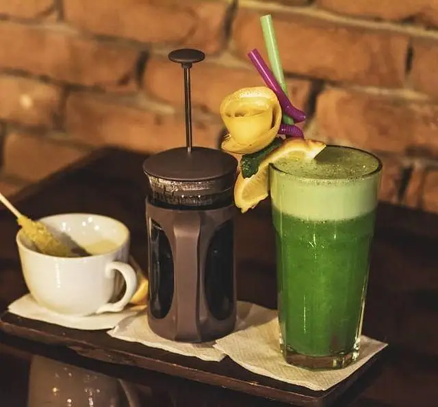 پذیرایی در کافه رستوران فروهر شامل یک فنجان نوشیدنی داغ، فرنچ پرس و یک لیوان آبمیوه سبز گوارا با تزئین لیمو و نی‌های رنگی.