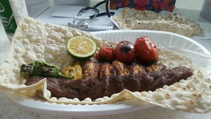 کباب کوبیده و حلیم ناصر، غذای سنتی ایرانی شامل کباب، گوجه کبابی، فلفل و نان لواش. تجربه غذایی لذیذ و باکیفیت.