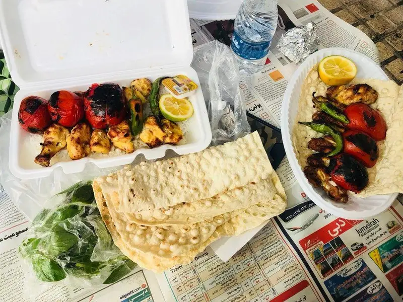 یک وعده غذای دلپذیر از کباب و حلیم ناصر، شامل جوجه کباب و کباب با گوجه و فلفل کبابی، نان تازه و سبزیجات.