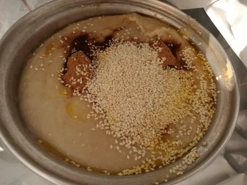 یک کاسه بزرگ حلیم سنتی داغ از کباب و حلیم ناصر با تزیین کنجد، دارچین و روغن، غذایی عالی برای صبحانه.