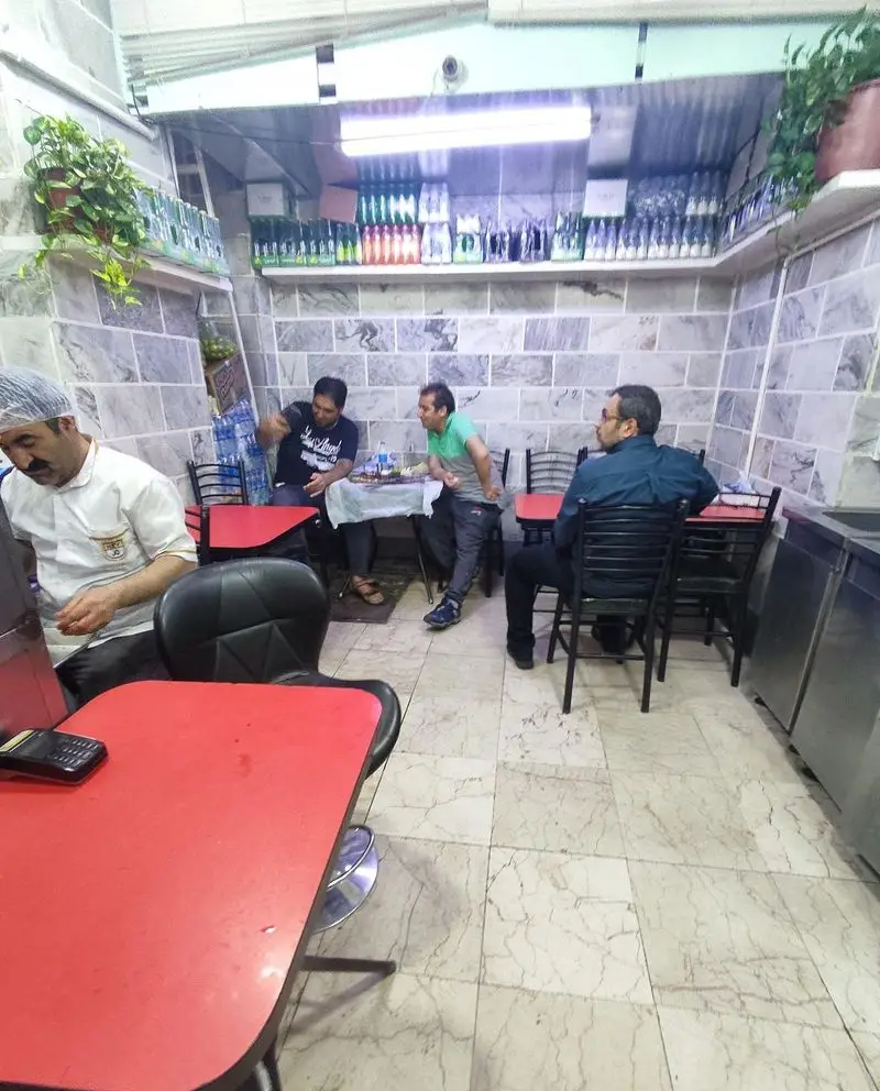 فضای داخلی جگرکی لوکس طلائی با مشتریانی که دور میزهای قرمز نشسته و در حال صرف غذا هستند. کارکنان در حال ارائه خدمات و قفسه‌های نوشیدنی در پس‌زمینه.